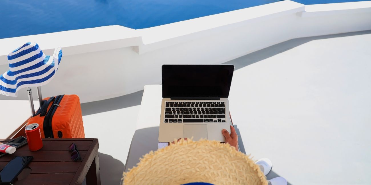 person in hat holding laptop enjoying the view 