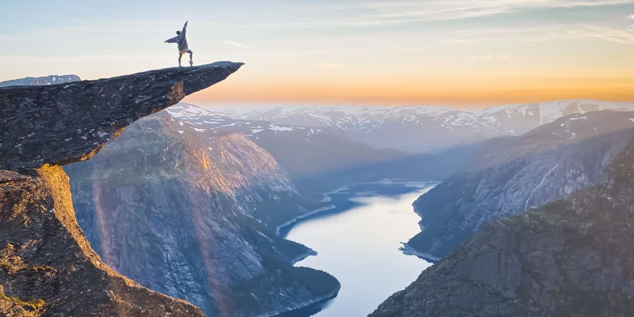 A person standing on the rock of Trollunga overlooking the fjord and surrounding mountains