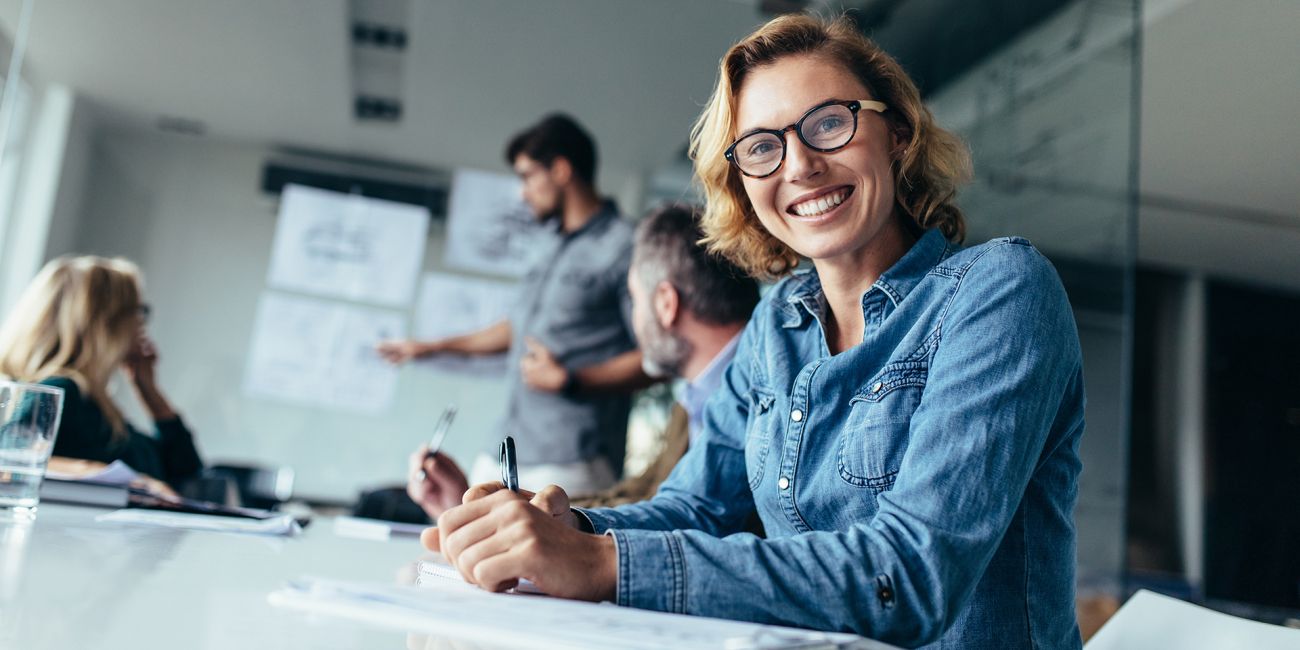 Smiling woman taking notes at a company meeting