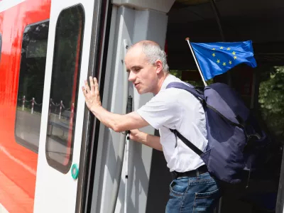 Man with disability holding European Union flag stepping out from train