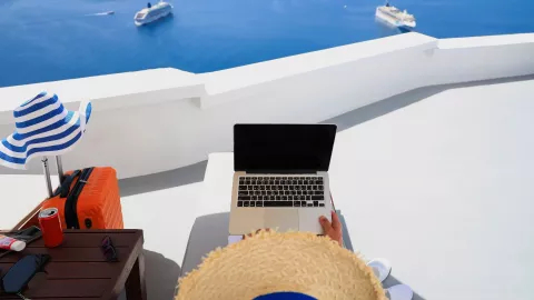 person in hat holding laptop enjoying the view 