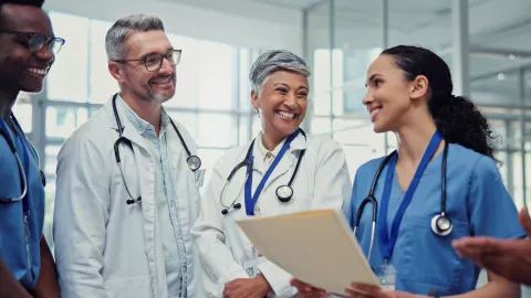 Documents, medical and smile of doctors with nurses in hospital together for collaboration or discussion. Agenda, healthcare and schedule with happy medicine team in clinic for brainstorming 