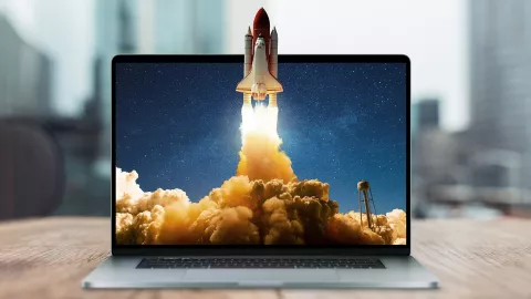Space rocket shuttle with a cloud of smoke and blast takes off from a laptop on a working office desk