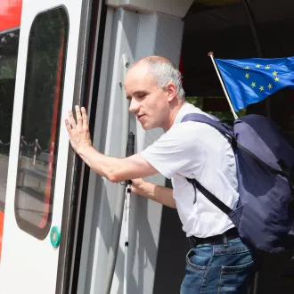 Man with disability holding European Union flag stepping out from train