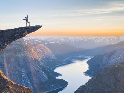 A person standing on the rock of Trollunga overlooking the fjord and surrounding mountains